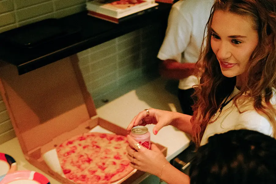 a woman standing next to a pizza box